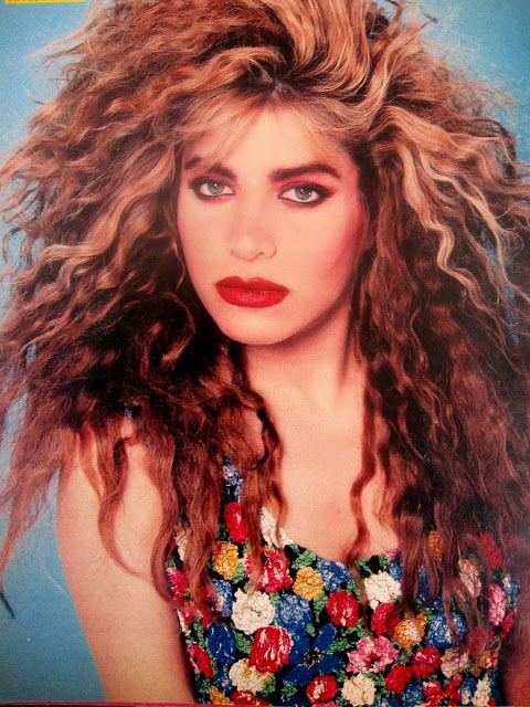 a woman with long, curly hair and blue eyes is posing for a magazine cover