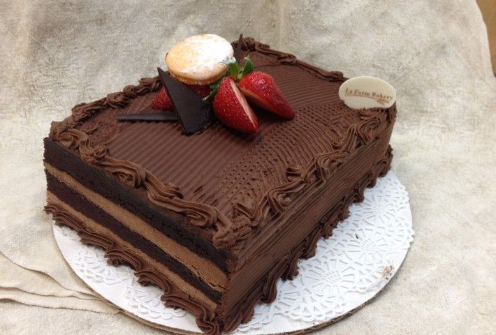 a chocolate cake with two strawberries on top is sitting on a white doily