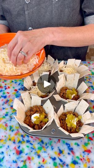 a person preparing food on top of a table with confetti in paper cups