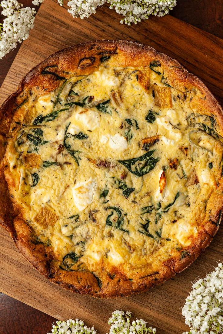 a pizza sitting on top of a wooden table covered in cheese and spinach toppings