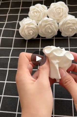 someone is decorating small white flowers with fake foam roses in the background, while another person holds out their thumb