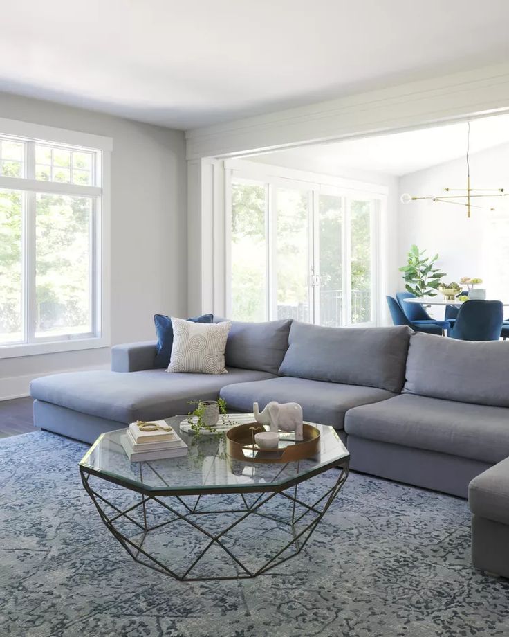 a living room filled with furniture and a glass table in front of a large window