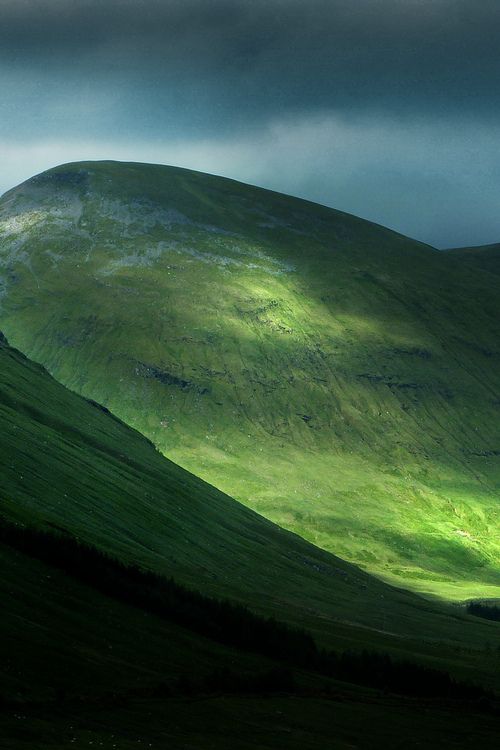 the green hills are covered in dark clouds