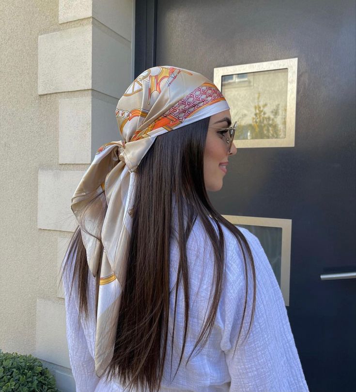 a woman with long hair wearing a scarf on her head is standing in front of a door