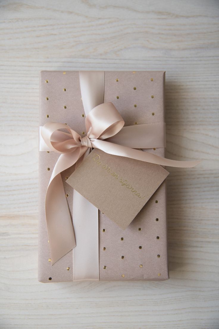 a gift wrapped in pink and gold paper with a bow on it's side