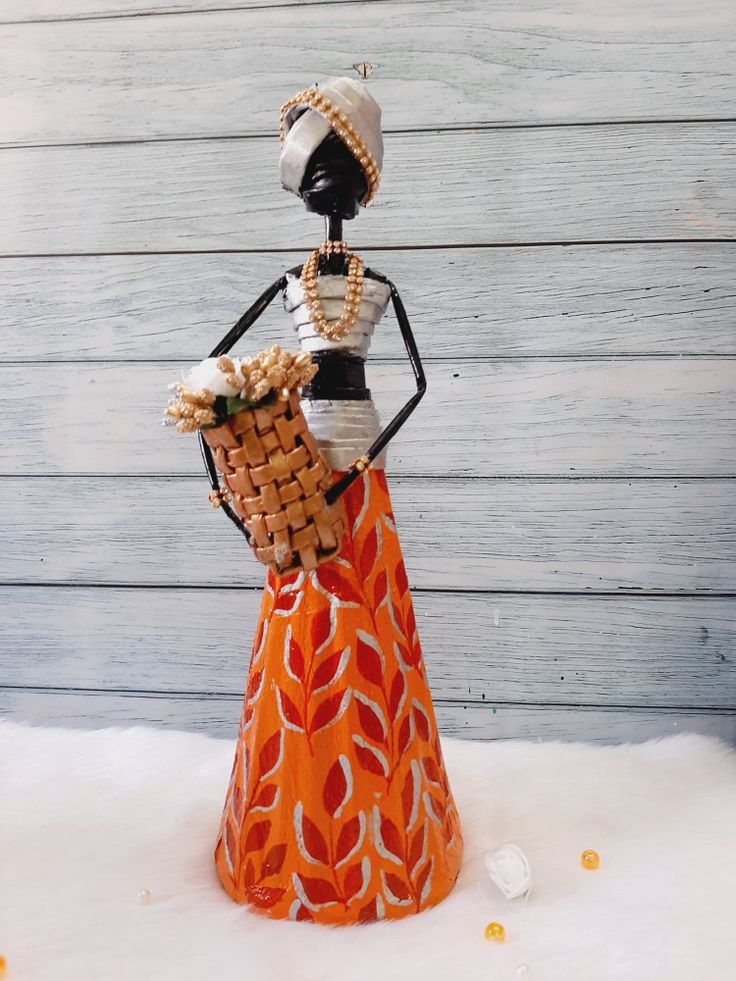 an orange and white figurine holding a basket in it's hands on top of snow