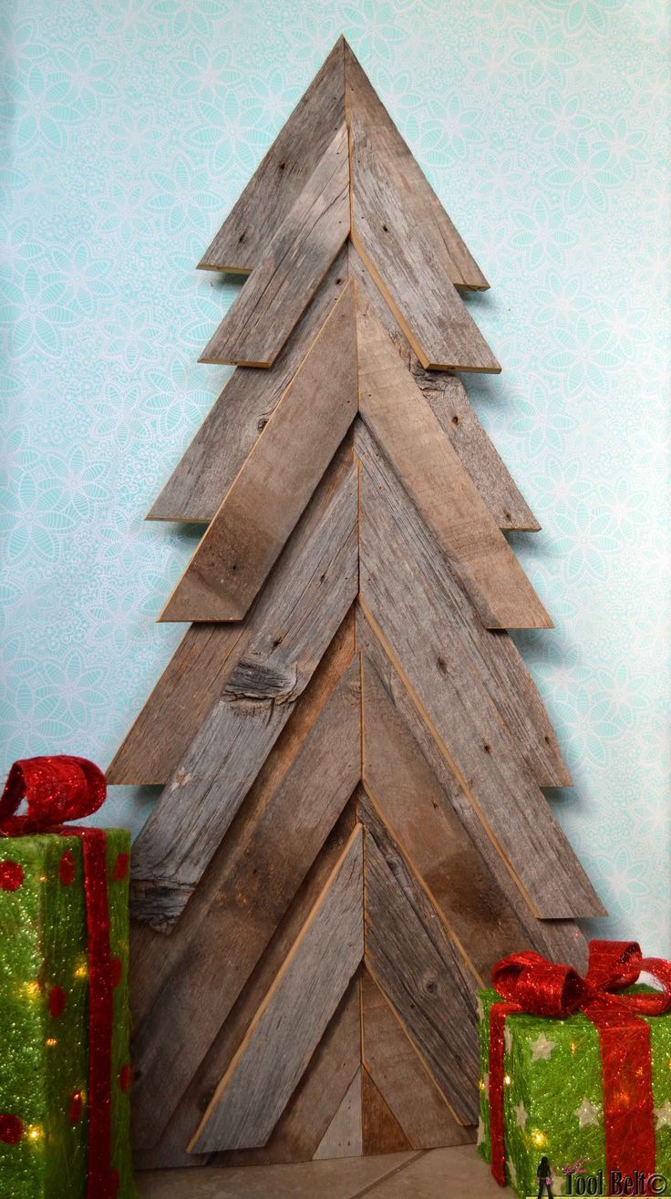 a wooden christmas tree made out of old wood planks with presents on the ground