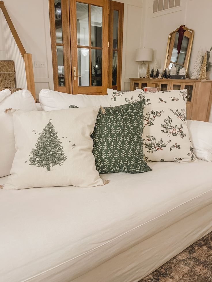 a white couch with pillows on top of it in front of a wooden dresser and mirror