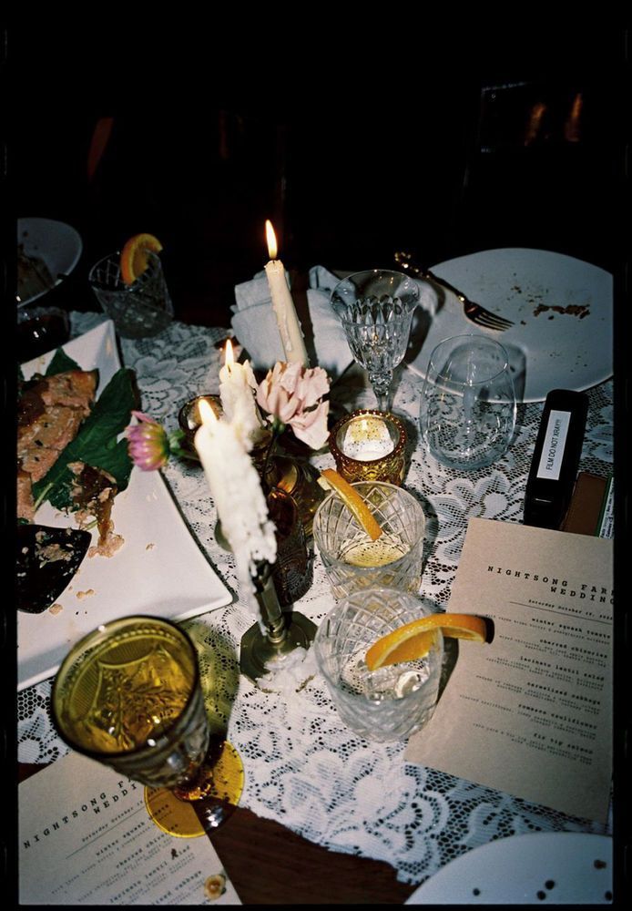 a table topped with plates and glasses filled with food covered in frosting next to candles