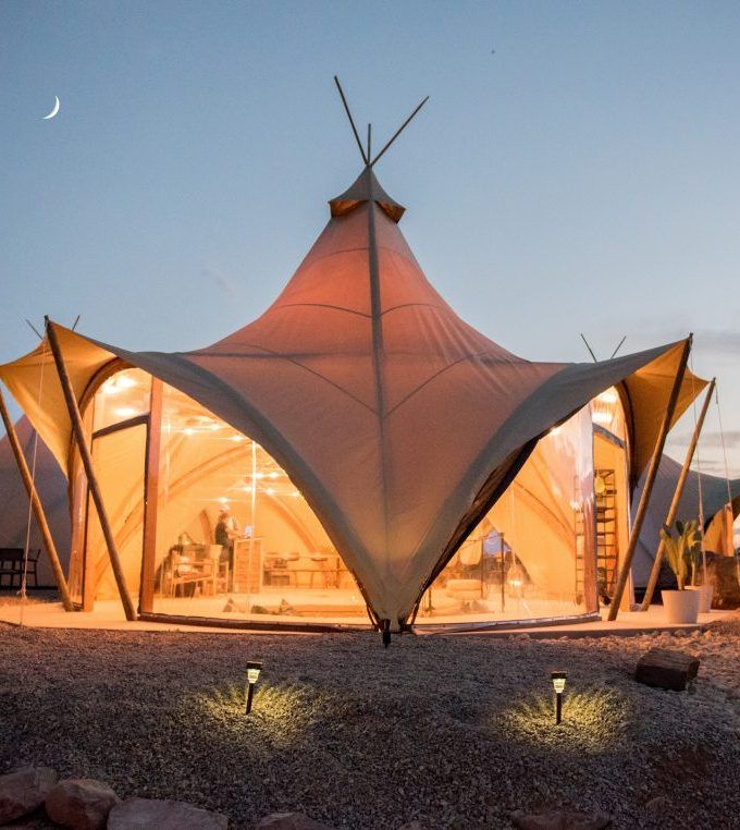 the tent is lit up at night in the desert