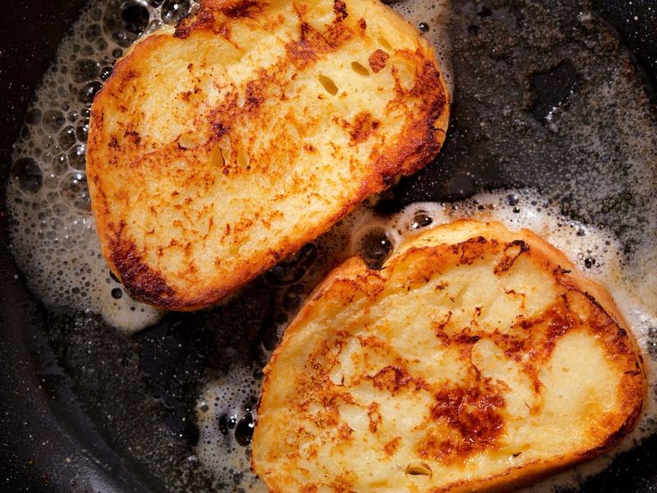 two pieces of french toast frying in a pan