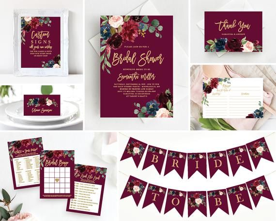 the wedding stationery is set up with burgundy and pink flowers, greenery, and bunting