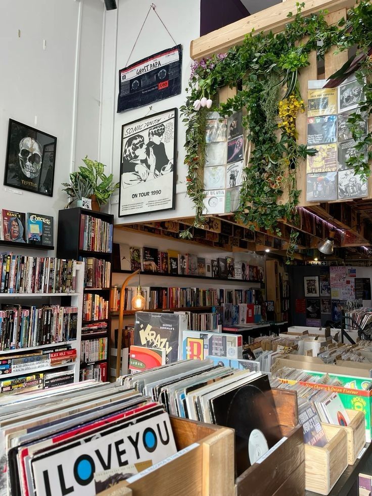 a room filled with lots of books and plants hanging from the ceiling next to each other