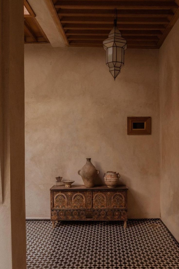 a room with a table and two vases on the floor next to a light fixture