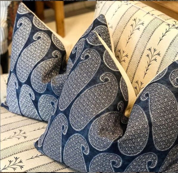 two blue and white pillows sitting on top of a bed