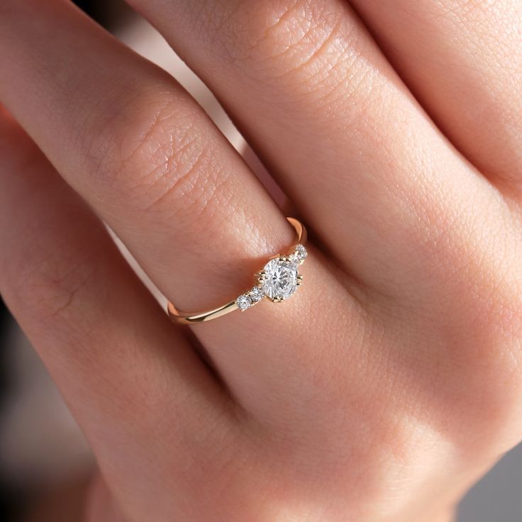 a woman's hand with a diamond ring on top of her finger and an engagement band