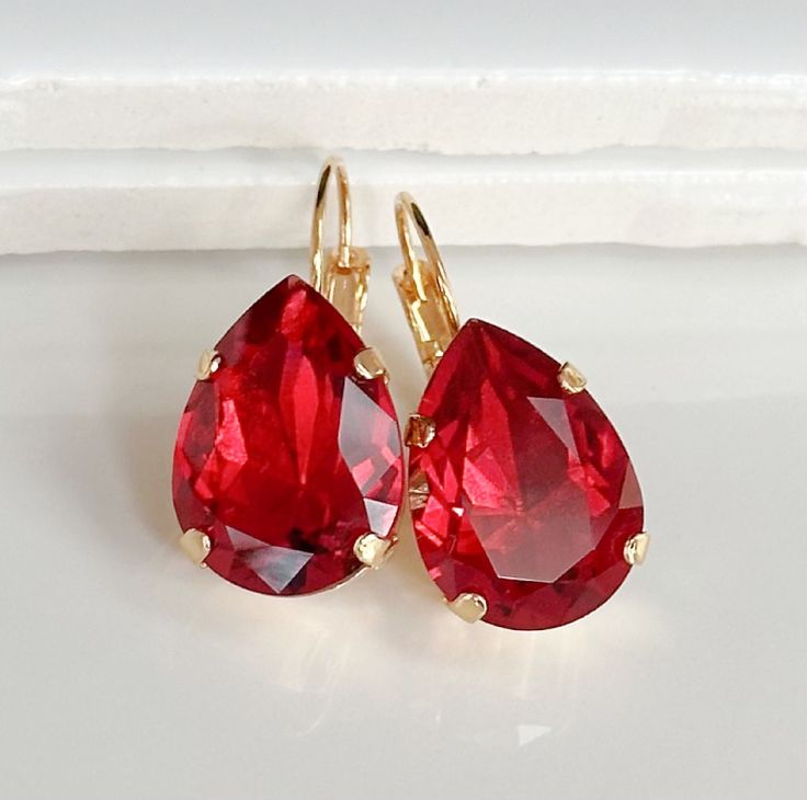 These gorgeous earrings display dazzling Red Rose crystal teardrops set in gold-plated bezels on gold lever back earrings.  Perfect for that special occasion!  Details: * Red Rose Crystal Clear Teardrops- 1/2x3/4"(13x18mm) * Gold-plated bezels and Earrings * Length- 1 1/4"(31mm) * Nickel and Lead-free These earrings come in a jewelry bag and gift box. Ruby Crystal Aesthetic, Gold Red Earrings, Gem Earring, Glam Earrings, Bridesmaids Jewelry, Crystal Teardrop Earrings, Red Pendants, Ruby Crystal, Red Jewelry