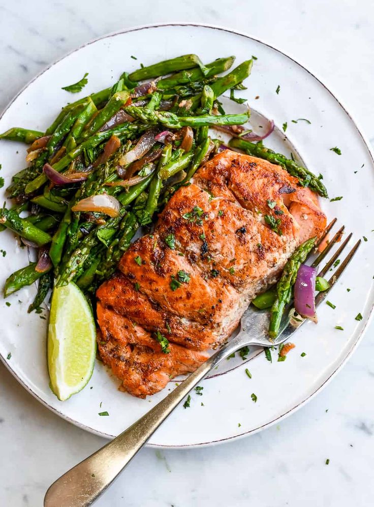 grilled salmon and asparagus on a white plate with a fork next to it