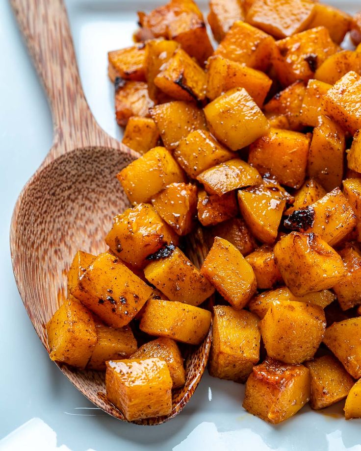 a white plate topped with cooked potatoes and a wooden spoon