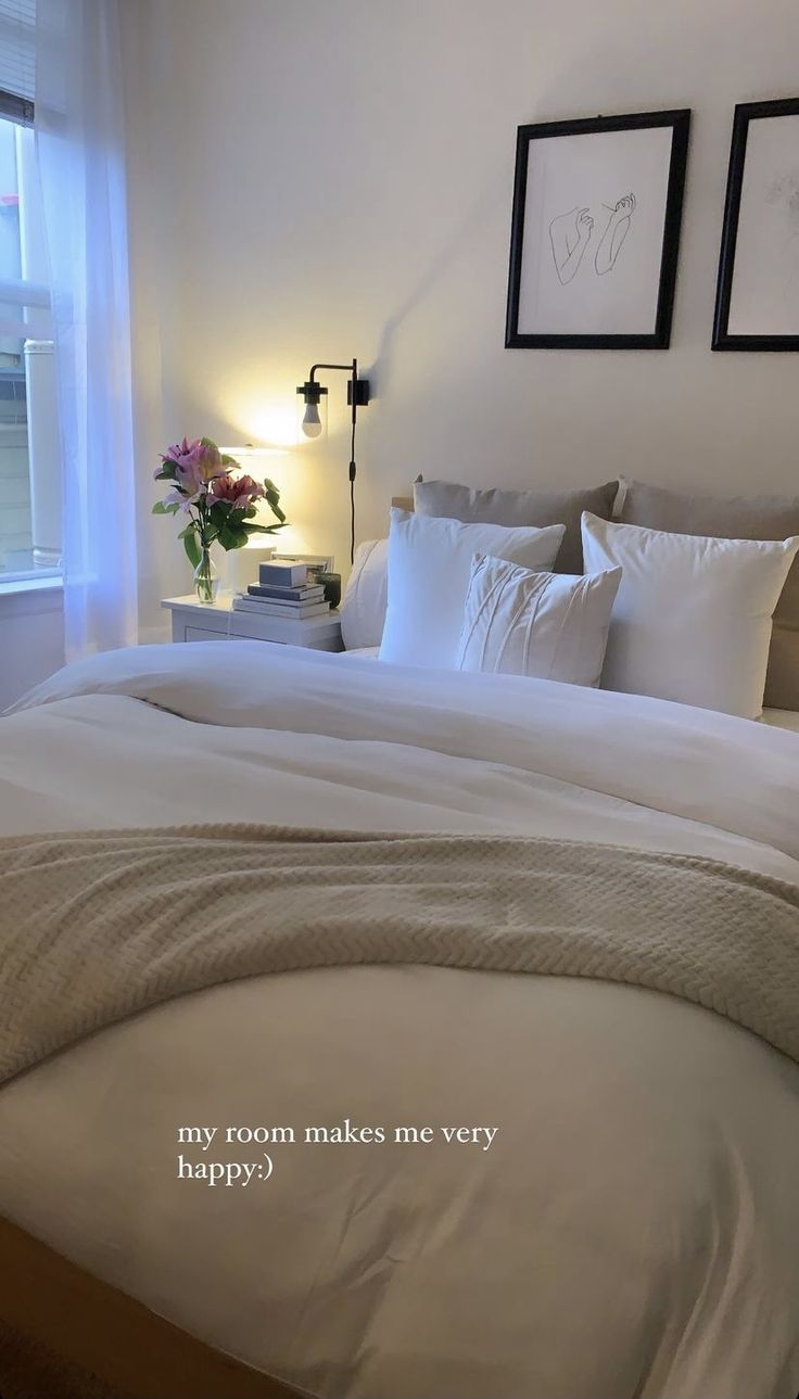 a bed with white sheets and pillows in a bedroom next to two framed pictures on the wall