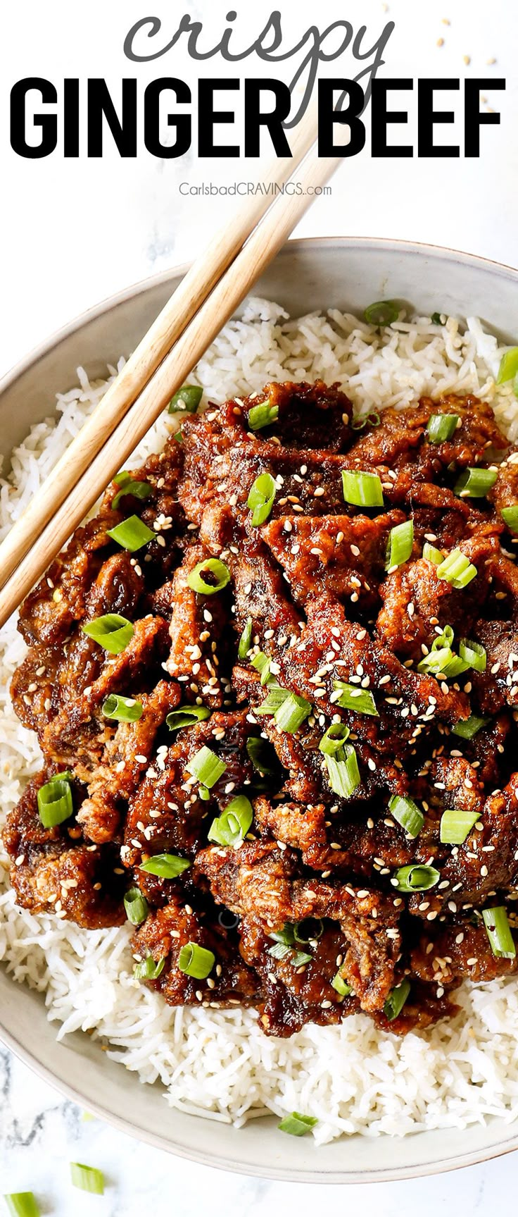 a white plate topped with meat and rice next to chopsticks on the side