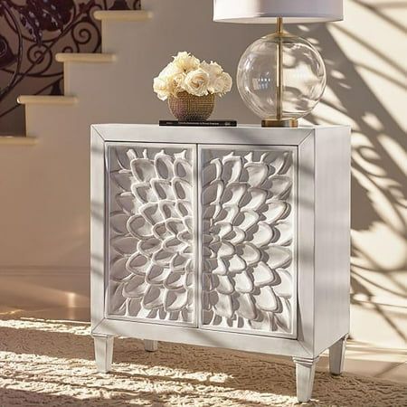 a white cabinet sitting on top of a carpeted floor next to a vase with flowers