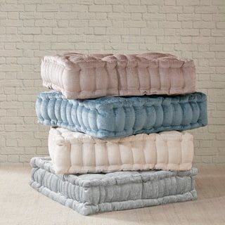 three pillows stacked on top of each other in front of a brick wall and floor