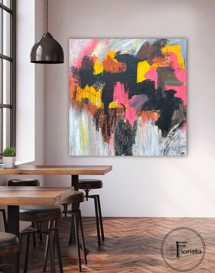 an abstract painting hangs on the wall above a dining room table