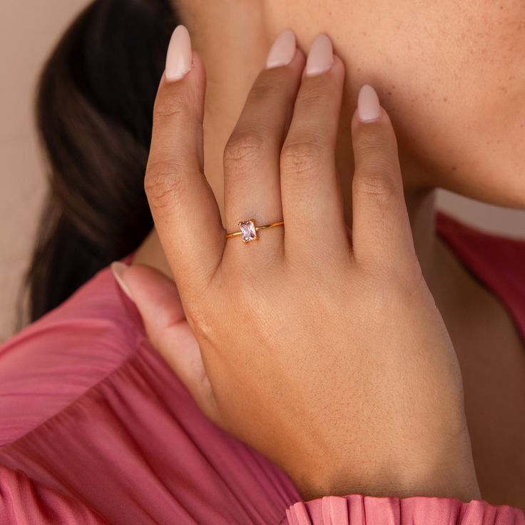 a close up of a person wearing a ring on her finger with a diamond in the middle