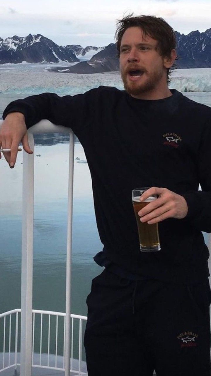 a man standing on a boat holding a beer