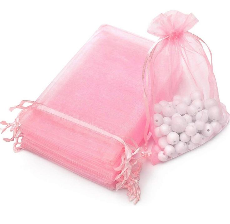 two bags filled with white and pink beads next to each other on a white surface