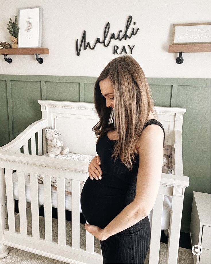 a pregnant woman standing in front of her crib