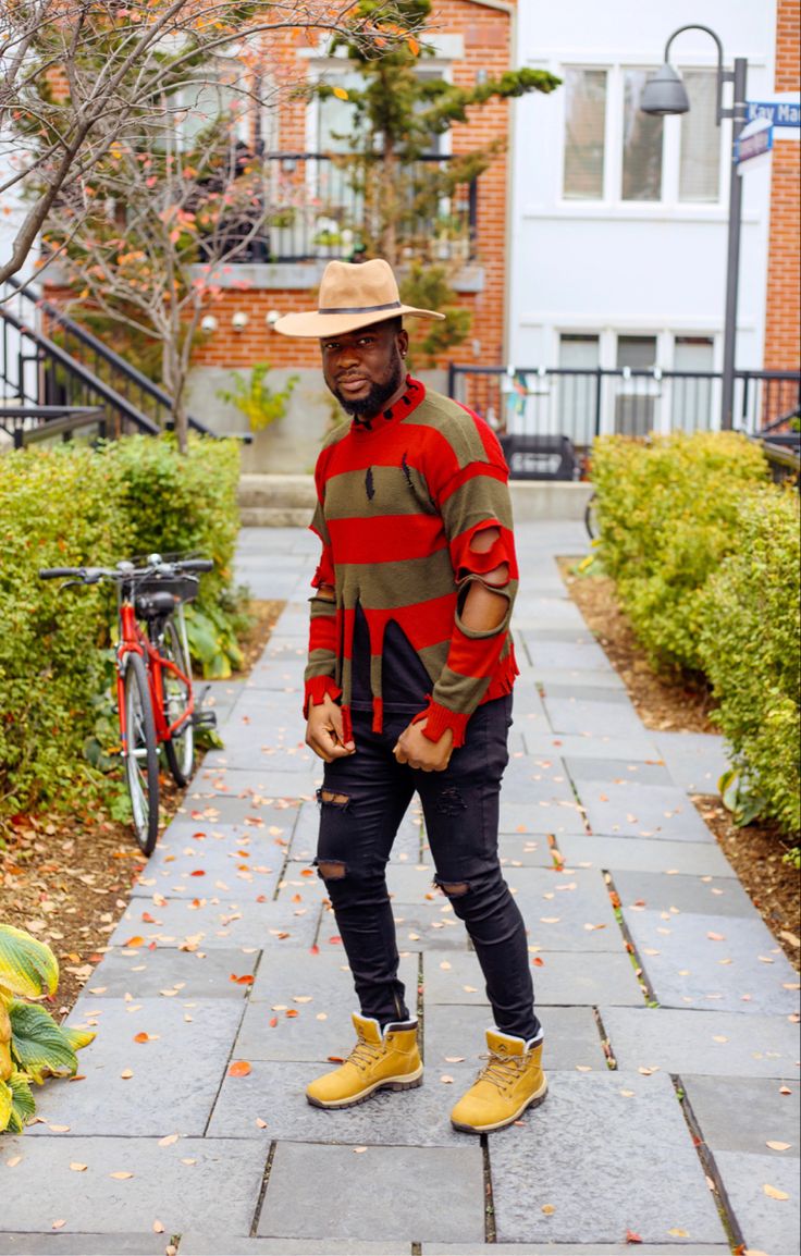 a man standing on a sidewalk wearing yellow shoes and a straw hat with his hands in his pockets