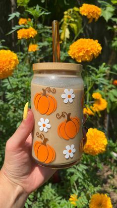 a hand holding a mason jar with flowers and pumpkins on it