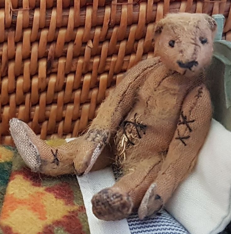 a teddy bear sitting on top of a blanket next to a basket