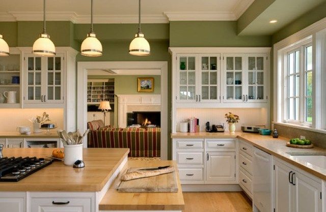 a large kitchen with white cabinets and wooden counter tops, along with an island in the middle