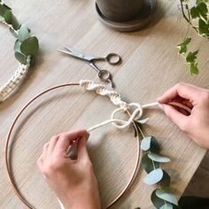 someone is making a wreath out of rope and leaves on a wooden table with scissors