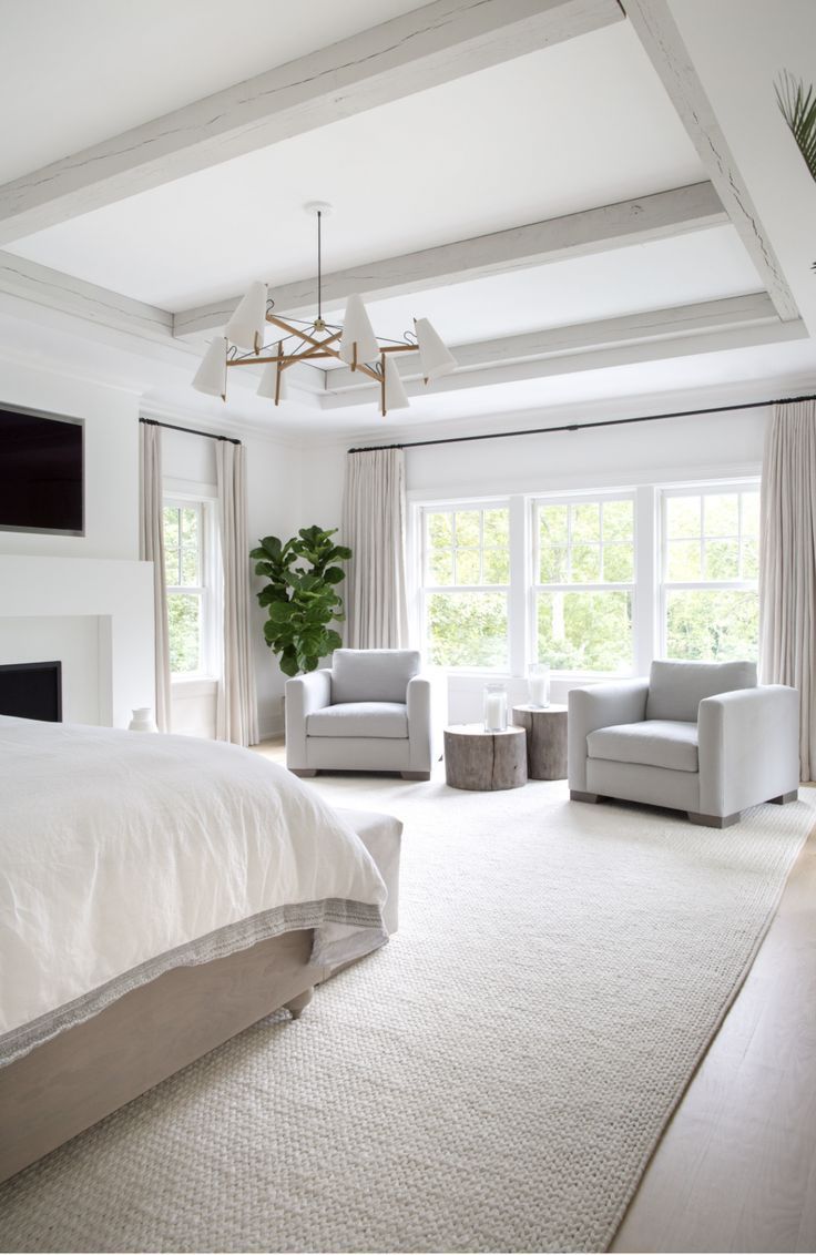 a bedroom with white furniture and large windows