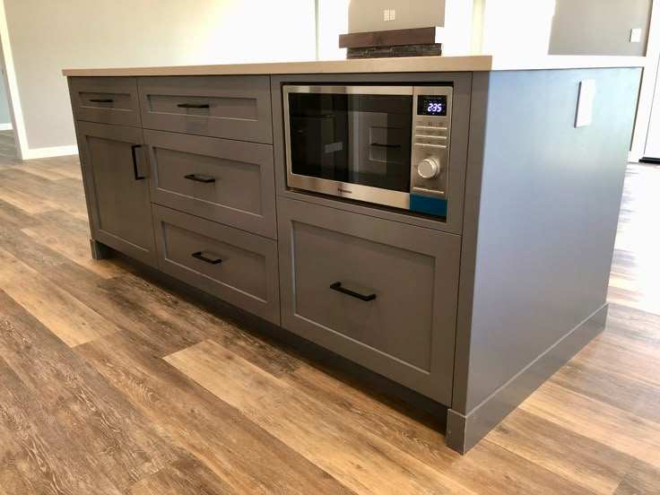 a microwave oven sitting on top of a wooden counter next to drawers in a kitchen