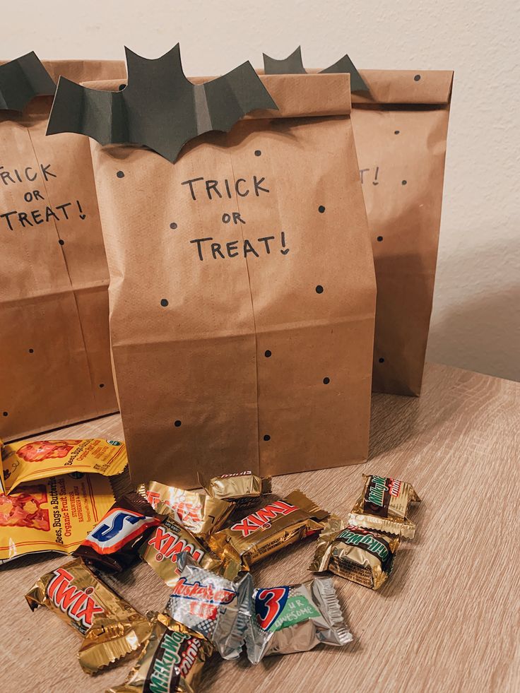 two bags with trick or treat on them sitting on a table next to some candy