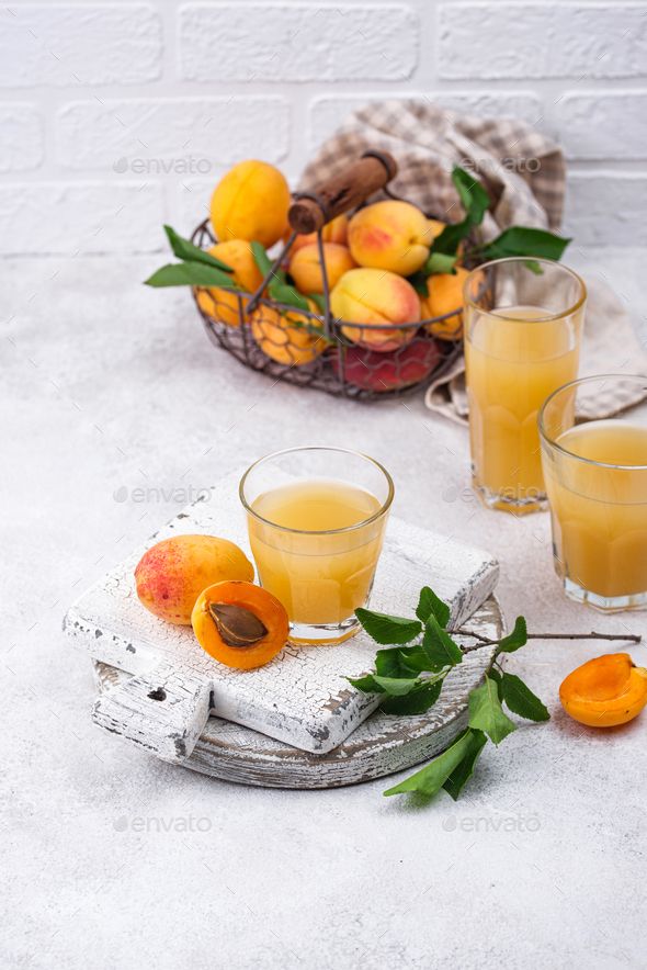 two glasses of orange juice and some fruit on a table