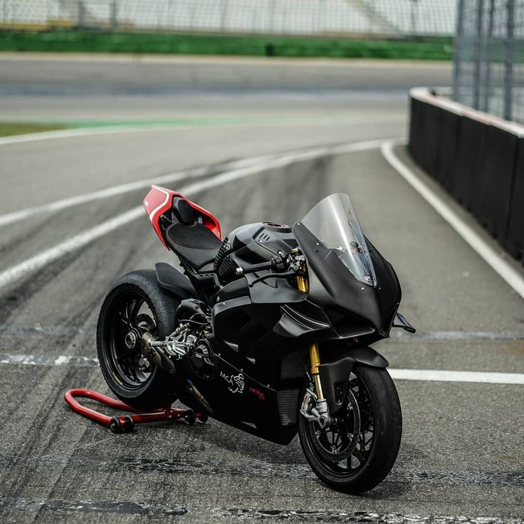 a black motorcycle parked on the side of a race track