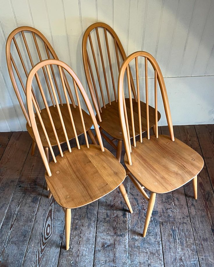 four wooden chairs sitting on top of a wooden floor