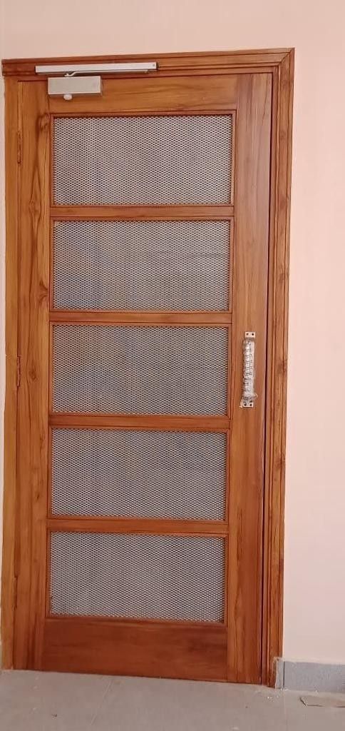 a wooden door with mesh screen on the front and side panels, in an empty room