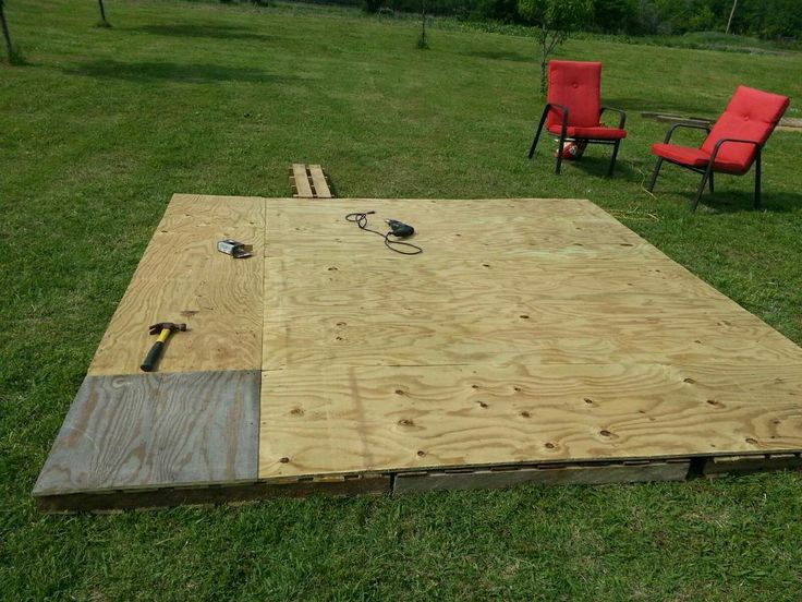 an outdoor area with two chairs and a table in the middle of it, surrounded by grass