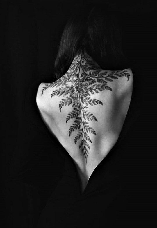 the back of a woman's neck with leaves on it