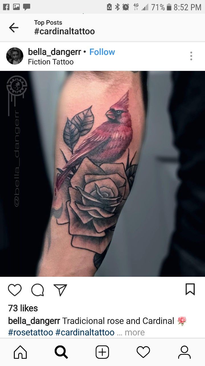 a red bird sitting on top of a rose tattoo