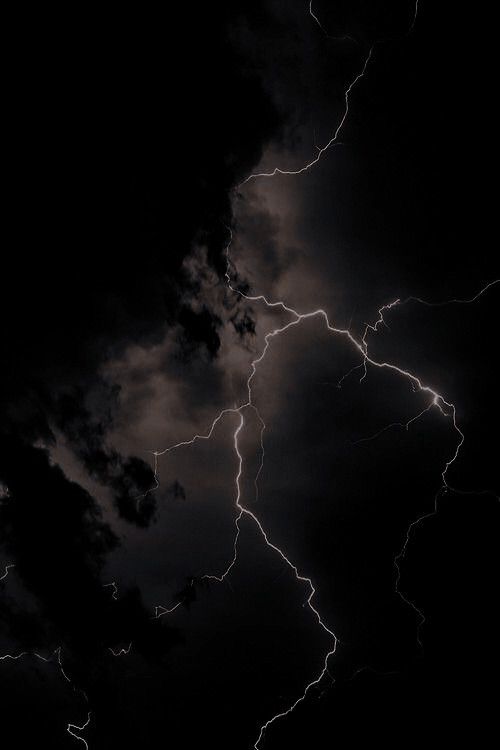 lightning strikes through the dark clouds in the night sky, making it look like they are about to strike