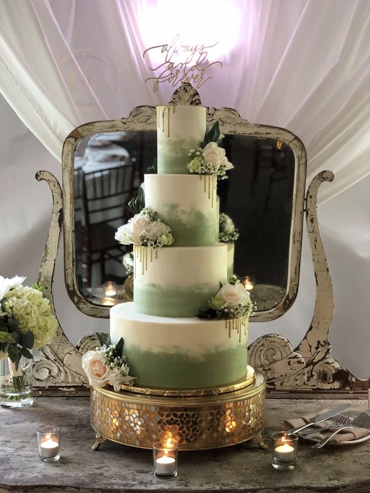 a three tiered wedding cake sitting on top of a table next to a mirror