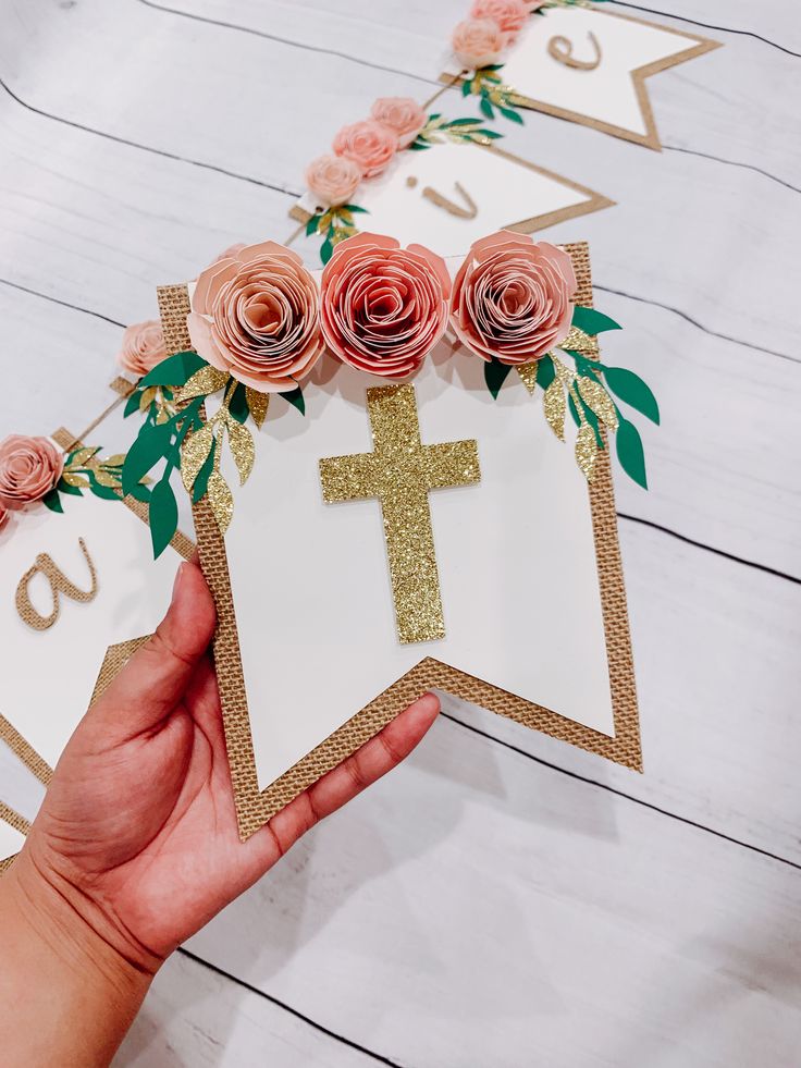 a person holding up a paper cross with flowers on it